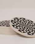 Stack of beige coasters with black circular and geometric pattern
